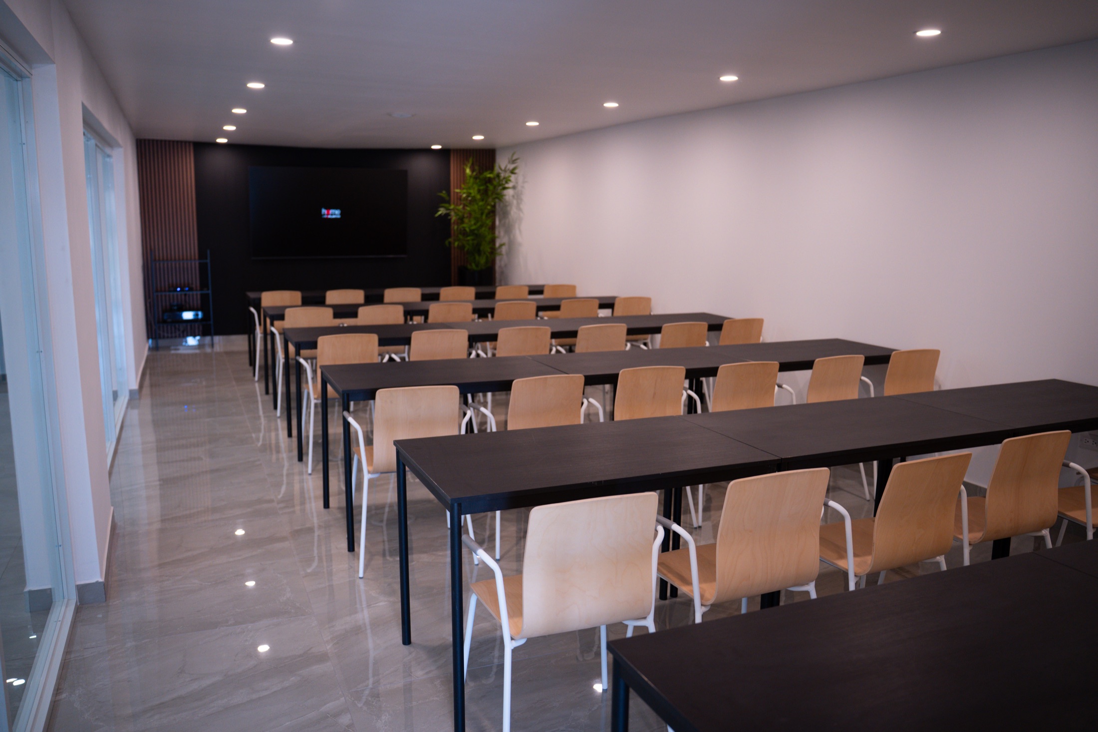 Interior de AQUA con mesas, sillas y pantalla